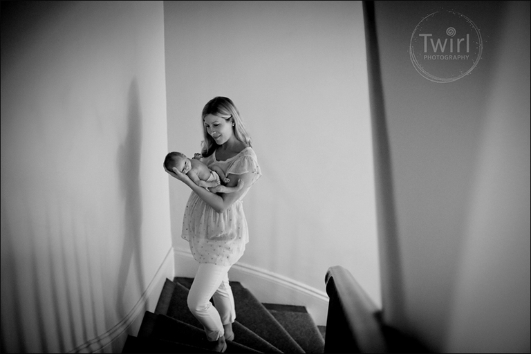 A mom walking up the stairs of her home while cuddling her newborn son.