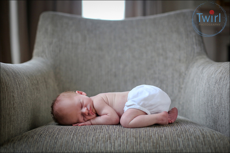 A sleeping newborn on a chair in the home of his family for a newborn photography session.