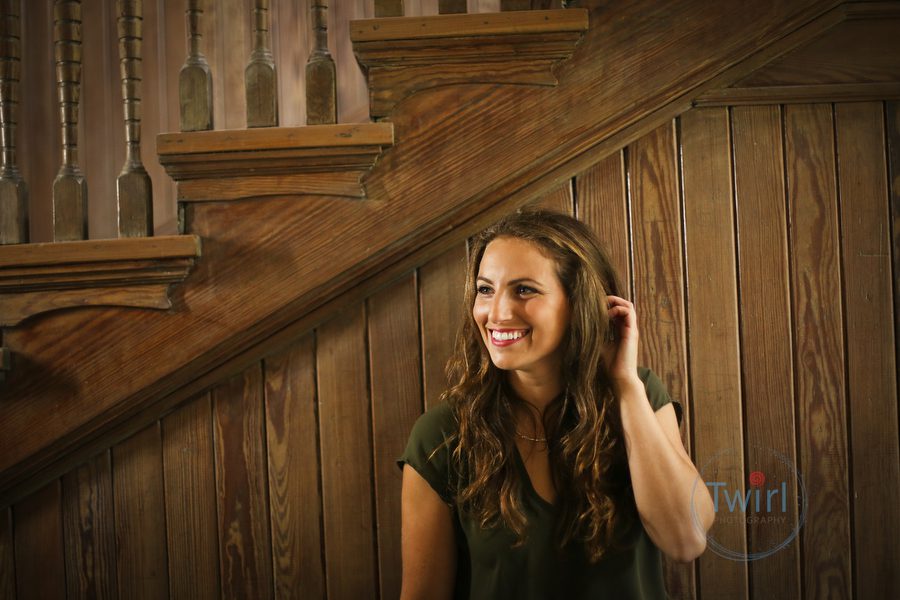 A woman touching her face with a wood staircasel behind her in at Tulane Univserity of New Orleans for a professional portrait and headshot.