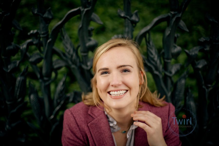 A headshot of a woman in front of a iron fence in the Garden District of New Orleans.