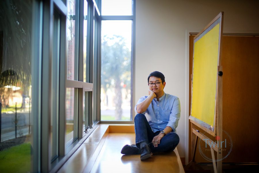 A graduate student at Tulane University sitting next to a window for a professional portrait in New Orleans.