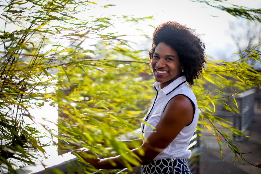 A woman standing next to a tree blowing in the wind wearing a white shirt for professional portrait.