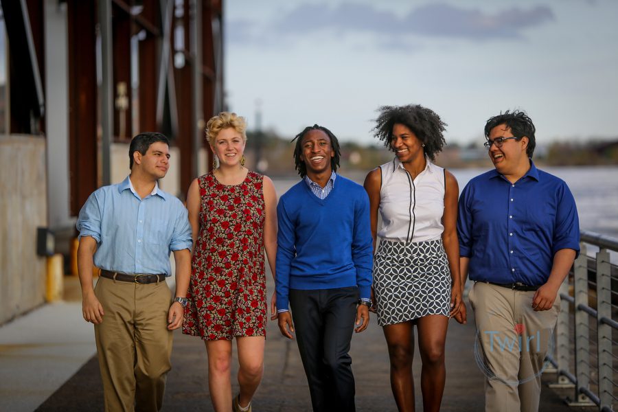 A group of young professionals walking along the Mississippi River for photos.