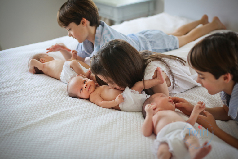 Triplet siblings look down and kiss their younger triplet newborn siblings at their home in New Orleans. 