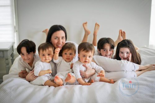 A mom with her 6 kids smiling.