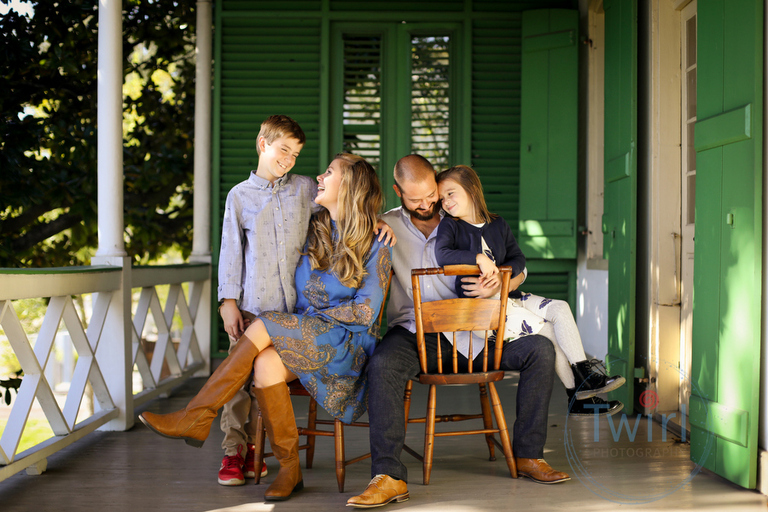 A family dressed in Fall colors sitting on a porch at the Pitot House for Family Portraits in New Orleans.