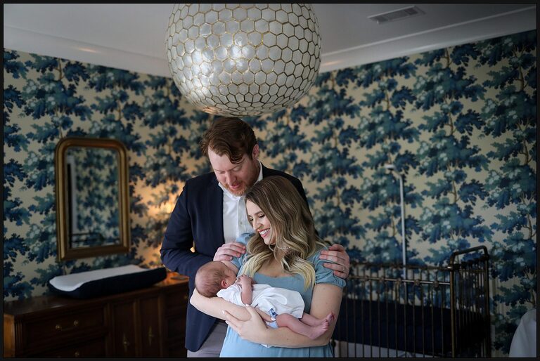 A mom and dad holding their newborn boy inside their decorated nursery at their New Orleans home.