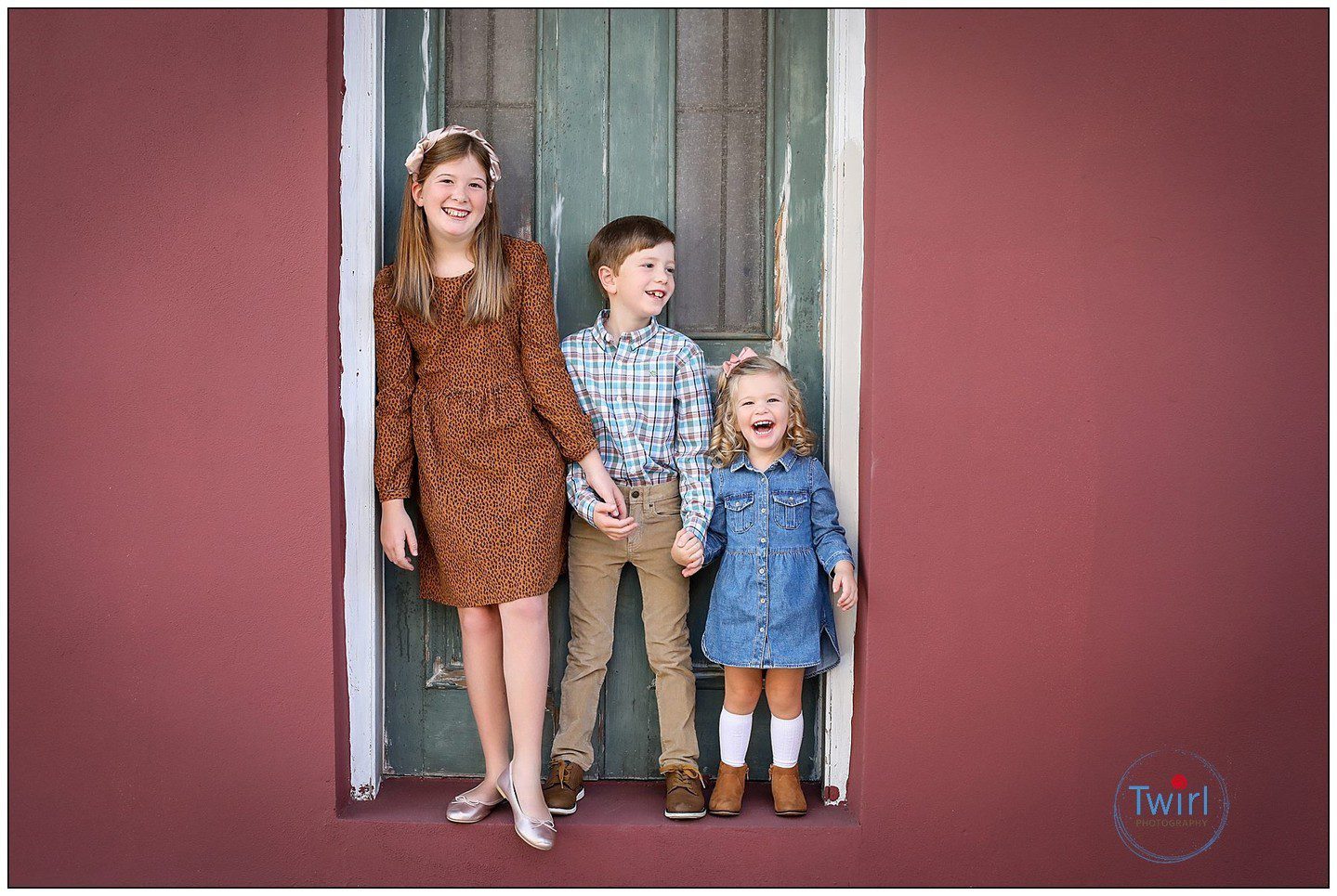 Three siblings standing in a doorway in the French Quarter for a portrait session in New Orleans.