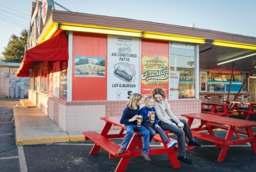 a group of people sitting on a red picnic table outside a restaurant