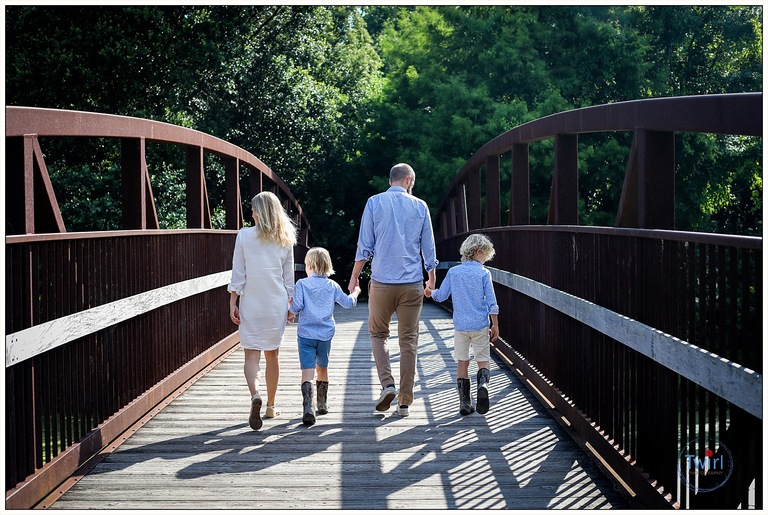 A family walking hand-in-hand over a bridge at Couturie Forest in New Orleans for photos.