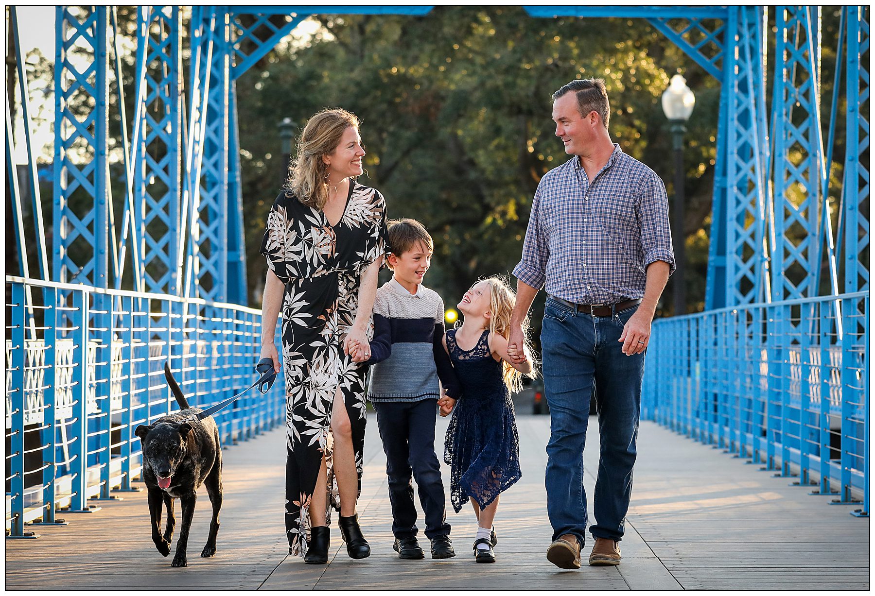 A family walks along a blue bridge over Bayou St. John for photos.
