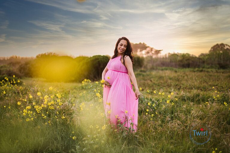Pregnant woman in a field of flowers and flowing dress for maternity pictures.