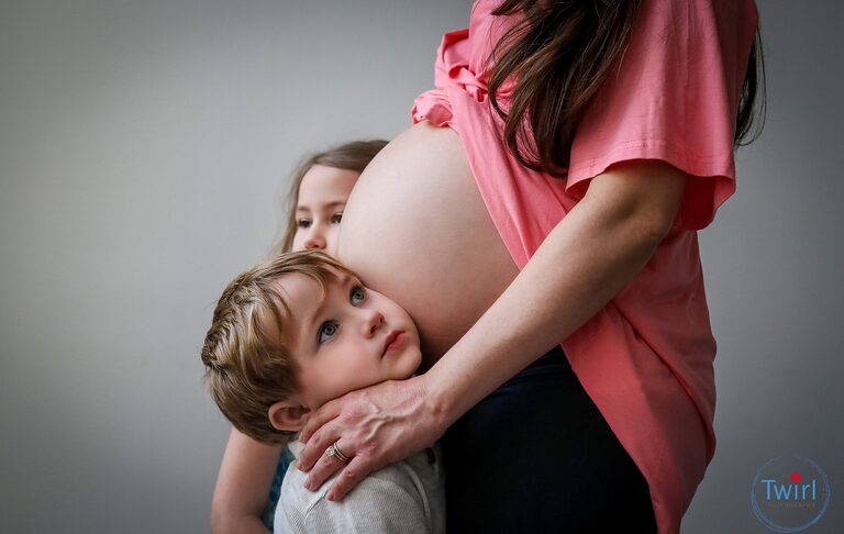 A little boy listening to his mom's pregnant belly as the family takes maternity photos in New Orleans.