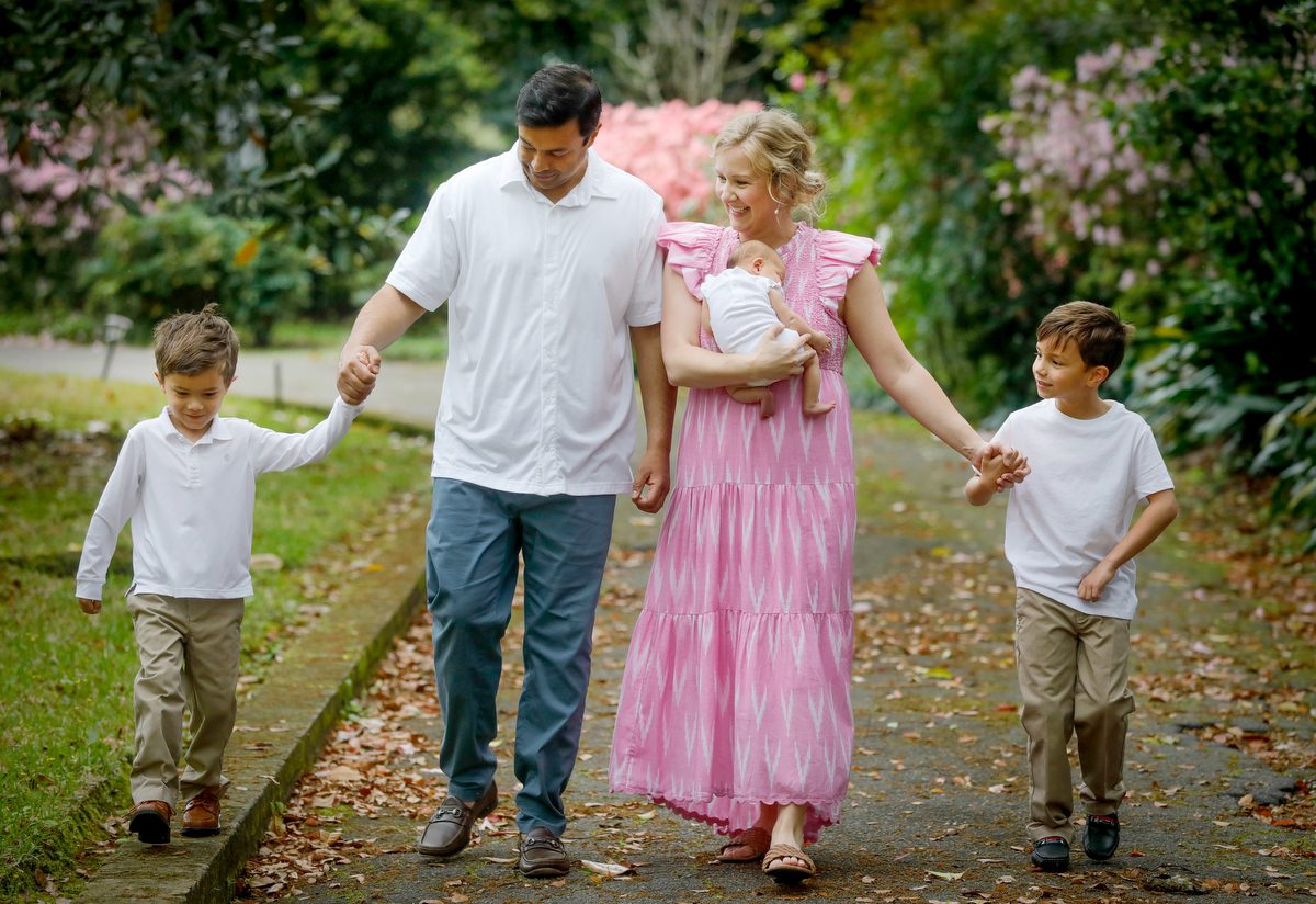 A family of five including 2 older brothers and a newborn sister walk in front of their home in New Orleans during a newborn photo session with Twirl Photography.