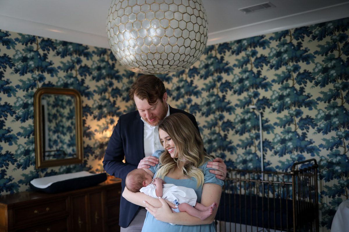 New parents hold their newborn son in the stylishly designed nursery in New Orleans, La. as they pose for lifestyle newborn photography by Twirl Photography.