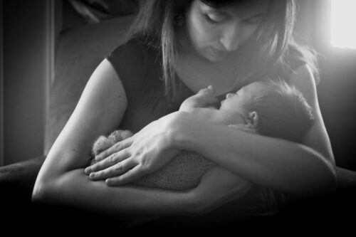 A mom cradling her newborn child in her arms.