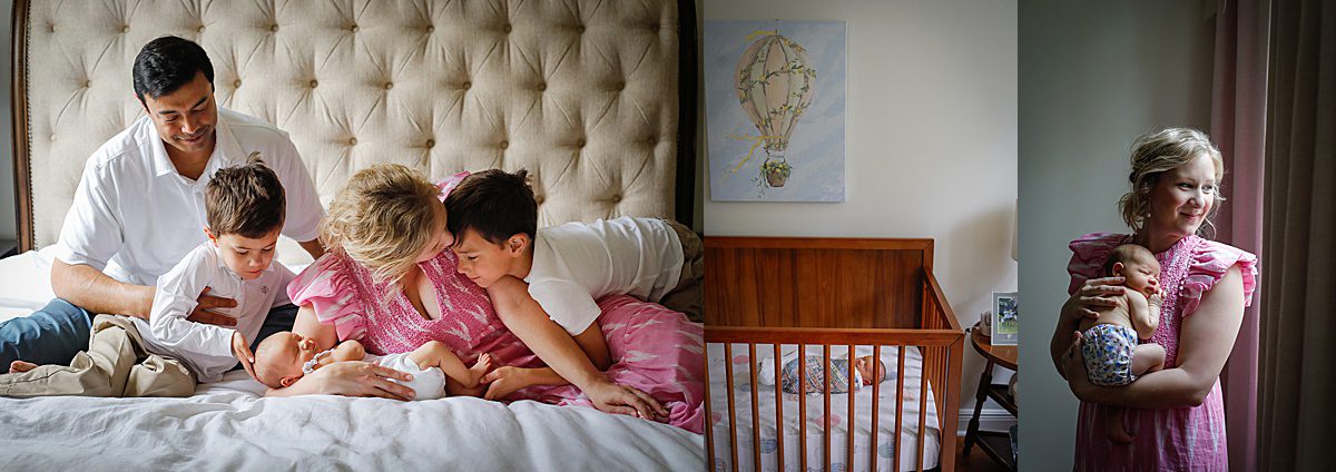 Mom and dad and two big brothers look down at their new baby sister as they sit on a bed.