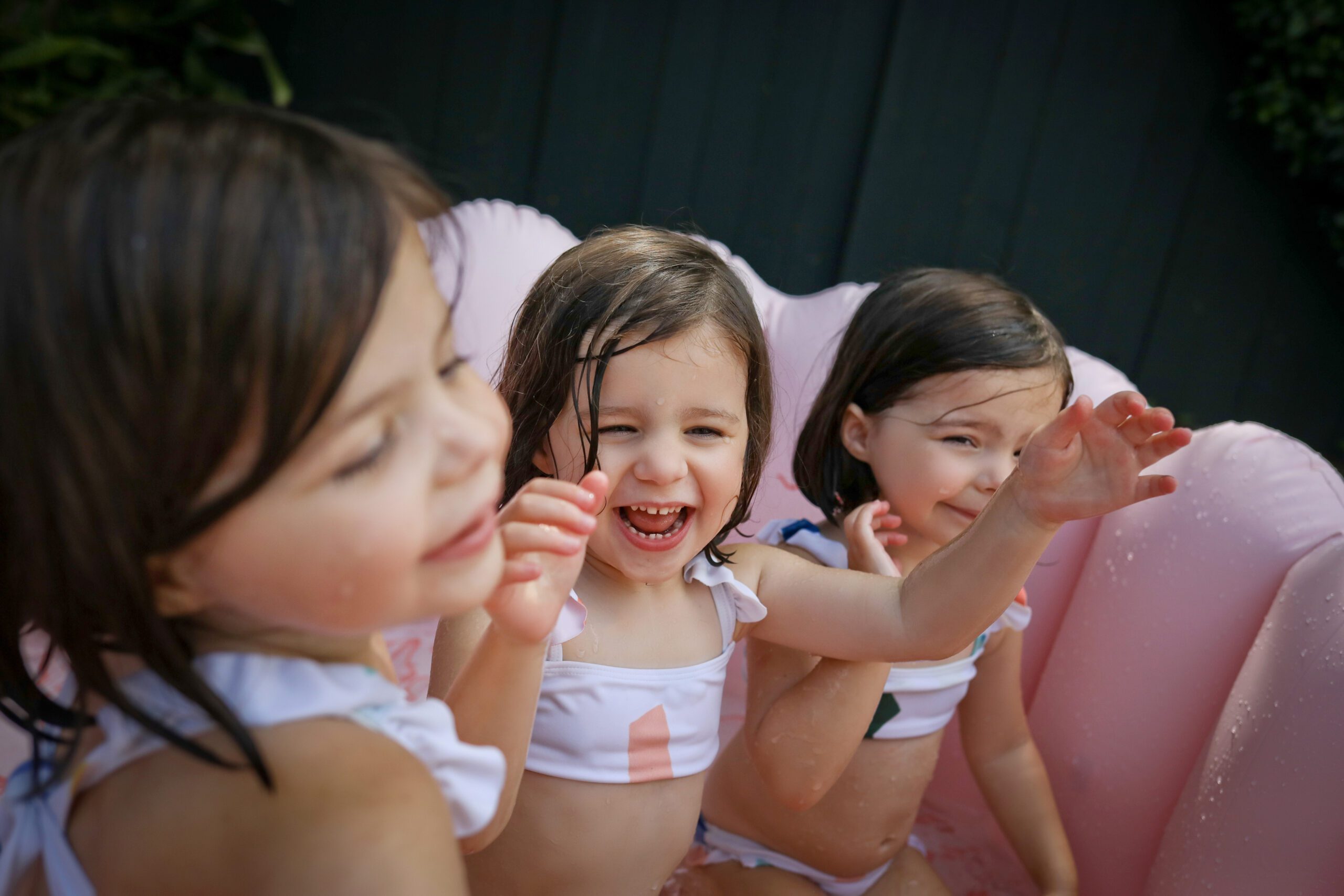 Triplet girls playing in a pool during fun family photos in summer in New Orleans.