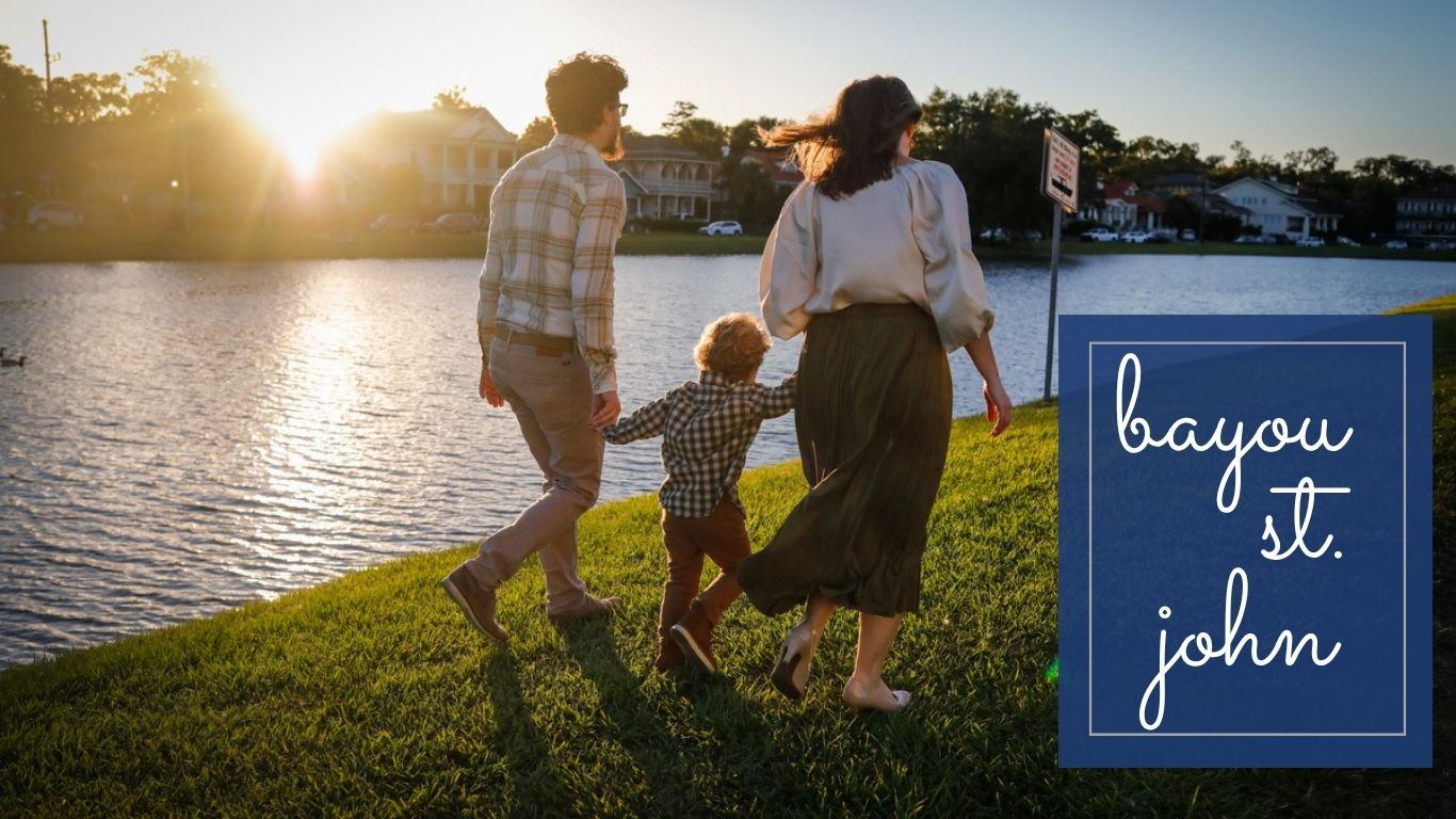 A family walking on the banks of a bayou in New Orleans holding hands.