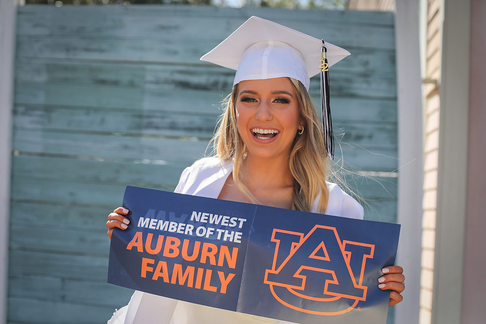 A high school senior holding a sign and smiling for Auburn University.