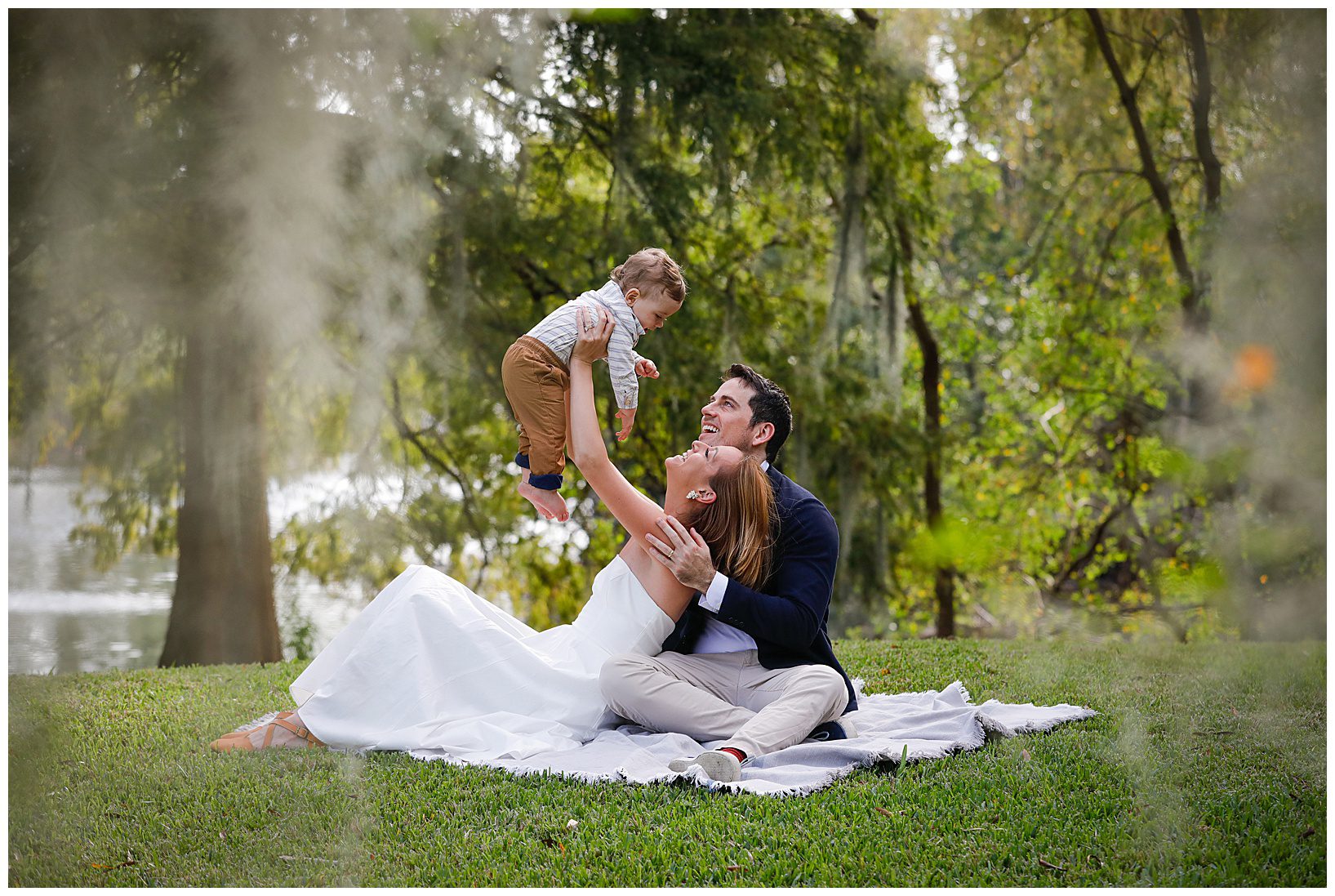 A mom lifts up her baby as they sit on a blanket in Audubon Park for pictures.