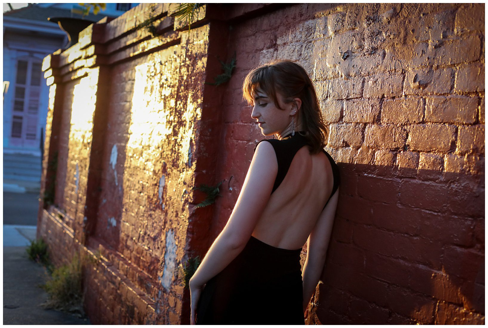 A high school senior looking over her shoulder wearing a jumpsuit with an open back for senior photos.