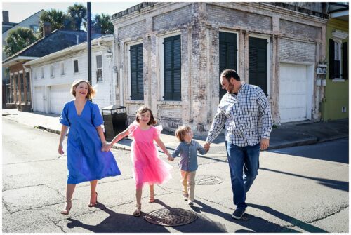 A family walking across the street in the French Quarter for pictures.
