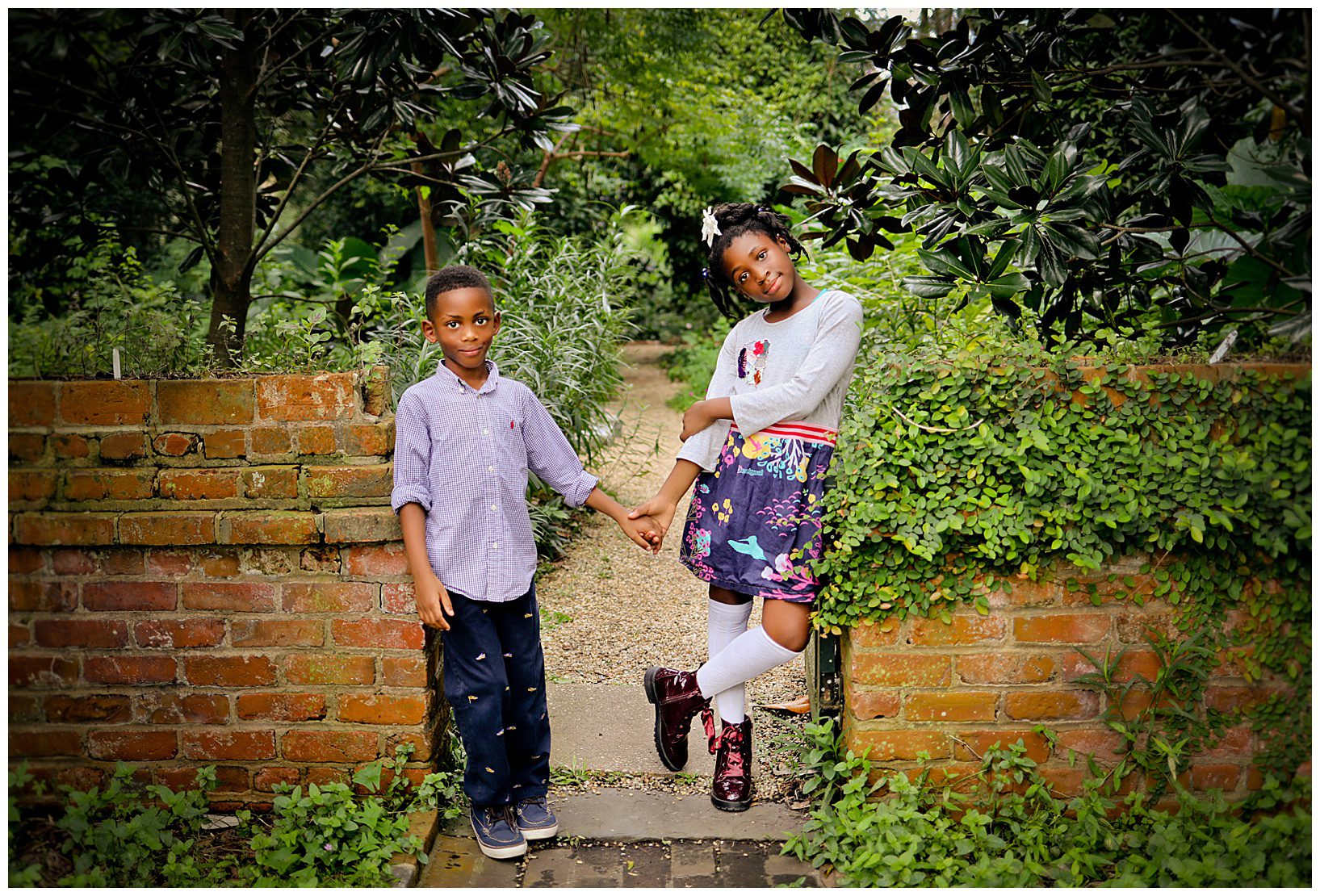 Two siblings holding hands in a garden.