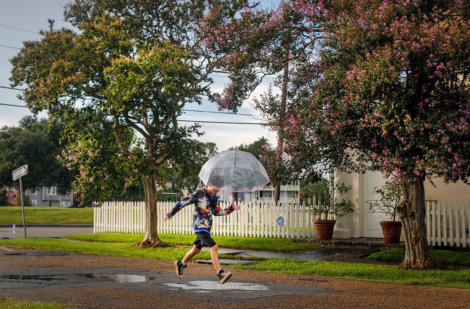 A boy jumping over a puddle.