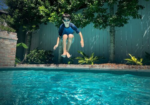 A boy jumping into a pool.