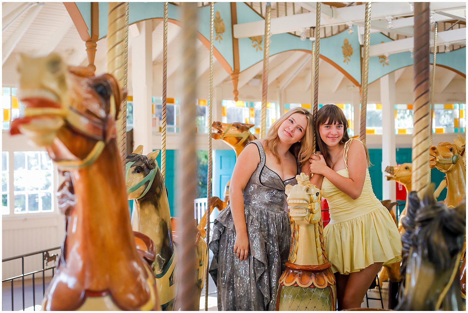 Two high school senior girls smiling on a carousel.