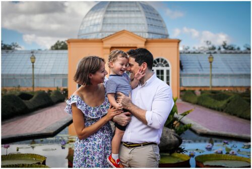 A mom and dad hugging their toddler as they are photographed. Story about the best New Orleans Botanical Garden Photo Spots.