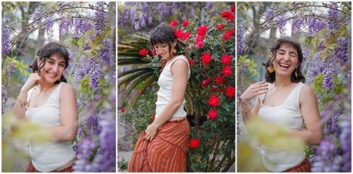 A senior posing for pictures surrounded by purple and red blooms.