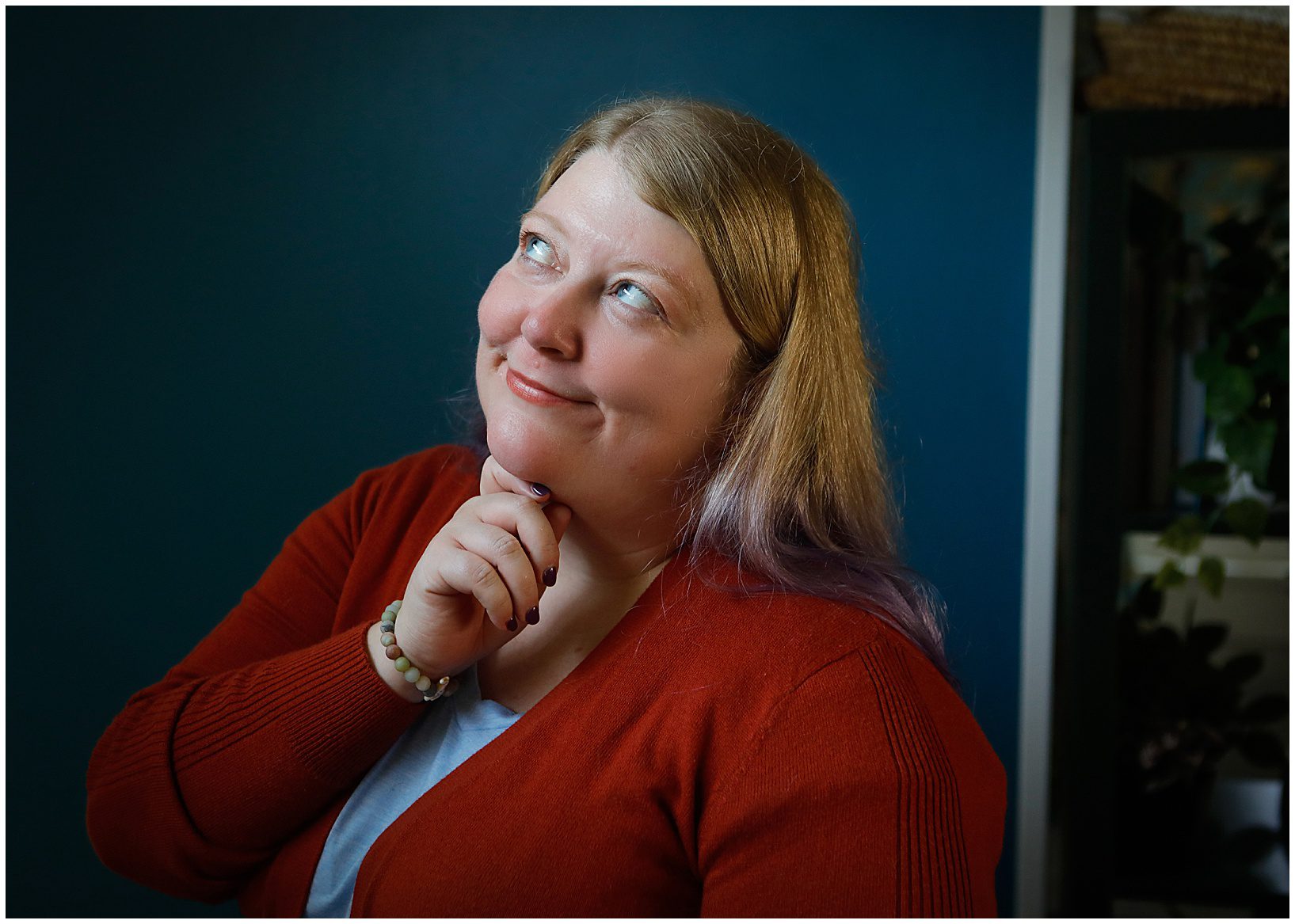 A woman wearing a red sweater looking up and smiling during a New Orleans headshot photo session in a studio..