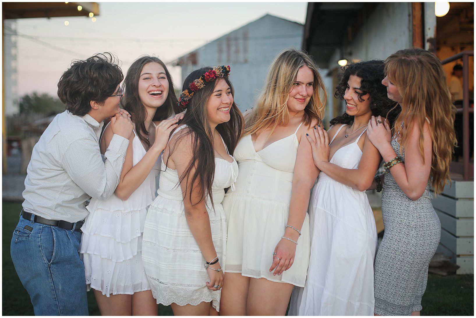 A group of high school senior girls wearing white laughing together for senior portraits.