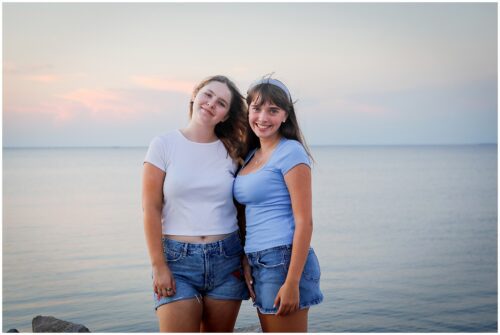 Two high school seniors standing next to each other for senior portraits near the lakefront.