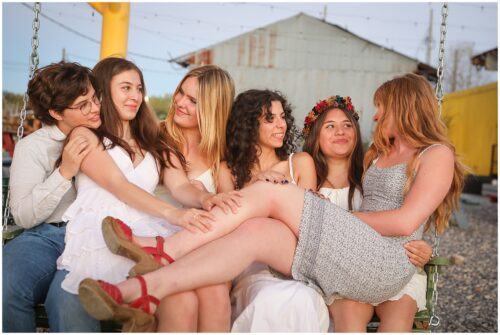 high school senior girls sitting together on a swing as they pose for senior photos in New Orleans.