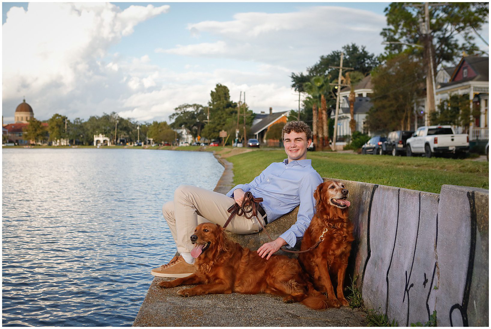 A high school senior boy with his two dogs looking out to a bayou.
