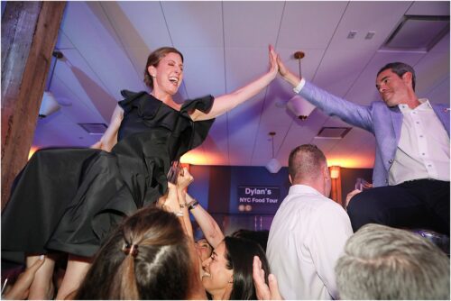 Parents being lifted on a chair during a hora dance for their son's bar mitzvah.